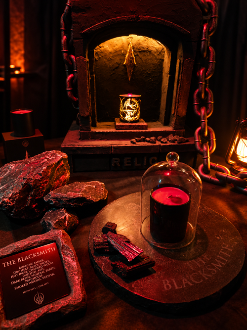 THE BLACKSMITH scented candle in a dark forge-inspired setting